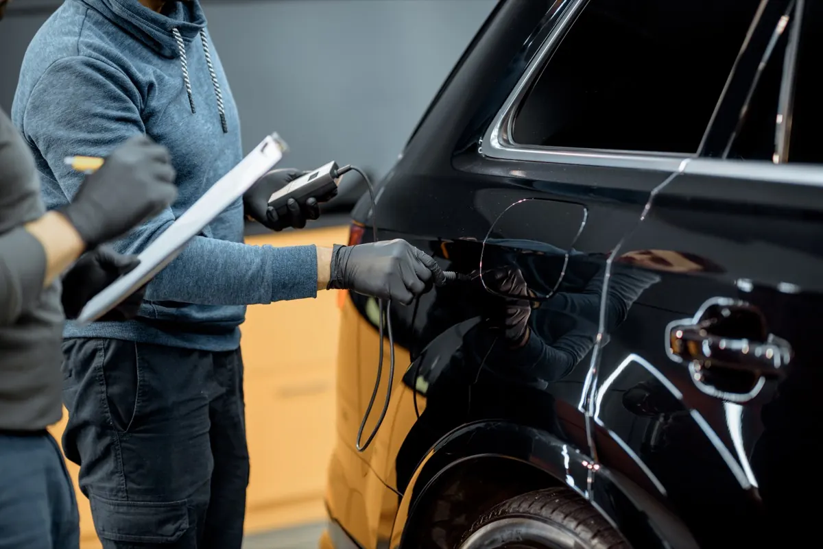 Technicians inspecting the front of a vehicle prior to ADAS sensor calibration